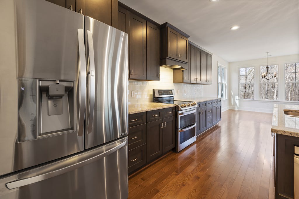 Spacious kitchen featuring stainless steel appliances and wooden cabinetry with natural light.